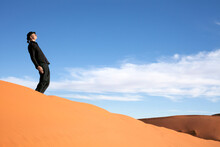 Morocco, Merzouga, Erg Chebbi, Man Wearing A Bowler Hat Standing Crooked On Desert Dune