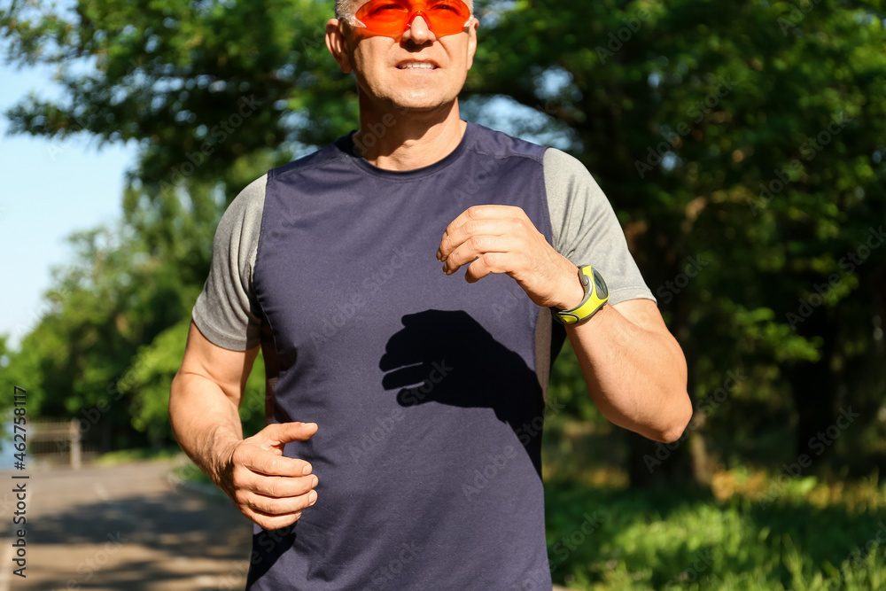 Sporty mature man with eyeglasses running in park
