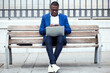 © Lifestock/Westend61 - Young businessman wearing blue suit jacket sitting on bench and using laptop