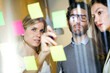 © Lifestock/Westend61 - Three business people brainstorming together with sticky notes on a glass wall