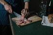 © Alberto Bogo/Westend61 - Hands of man cutting salami slices on board at table