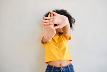 Woman Showing Stop Gesture While Standing Against White Wall