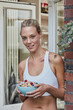 © Roger Richter/Westend61 - Portrait of smiling sporty young woman with muesli bowl at house entrance