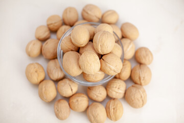 Aufkleber - A lot of whole walnuts in a cup on a white background close-up. Healthy, organic food with a high content of protein and protein.
