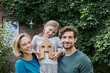 © Roger Richter/Westend61 - Portrait of happy family in front of their home with house model