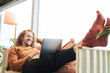 © Jo Kirchherr/Westend61 - Smiling man using laptop while lying on sofa at home
