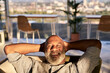 © Jo Kirchherr/Westend61 - Smiling mature man relaxing on sofa at building terrace during sunset