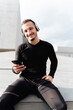 © Francesco Morandini/Westend61 - Young man wearing headphones smiling while using mobile phone sitting outdoors
