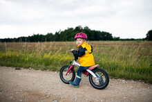 Toddler Girl With Pink Cycling Helmet On Balance Bicycle
