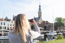 Netherlands, Zeeland, Veere, Woman Taking Photo Of Old Town