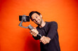 © Daniel Waschnig/Westend61 - Cheerful man taking selfie while holding gimbal with smart phone against orange background