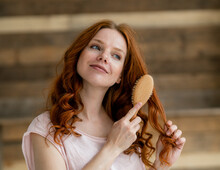 Portrait Of Smiling Redheaded Woman Brushing Her Hair