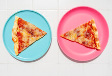 Two Slices Of Pizza Margherita On Blue And Pink Plates