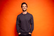 © Daniel Waschnig/Westend61 - Happy handsome man with hands in pockets against orange background
