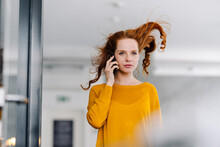 Woman with windswept hair on the phone in office