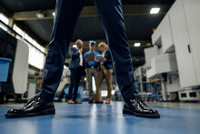 Business People And Worker Talking In A Factory Seen Through Legs Of A Businessman