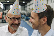 © KNSY/Westend61 - Portrait of two happy businessmen wearing party hats in a factory