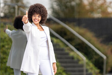 Confident Businesswoman Showing Thumbs Up While Standing Against Glass Wall At City
