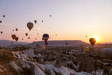Colorful Hot Air Balloons Flying Over Rocky Landscape At Sunset In Goreme, Cappadocia, Turkey