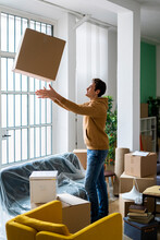 Playful Young Man Throwing Cardboard Box While Moving Into New Home
