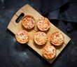 © Westend61 - Cutting board and mini pizzas with cheese, tomatoes and ham