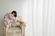 © Gala Mart√≠nez L√≥pez/Westend61 - Woman in nightwear sitting on armchair at home