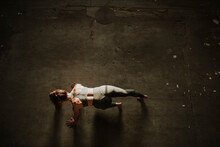 Woman Exercising On Floor At Abandoned Factory