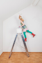 Mature Woman Painting Wall While Standing On Step Ladder At Home