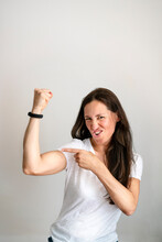 Portrait Of Cheerful Mature Woman Pointing At Bicep Against White Background