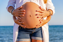Midsection Of Pregnant Woman With Son Touching Belly At Beach