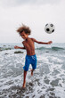 © DREAMSTOCK1982/Westend61 - Boy playing with a football on the beach