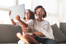 Mother And Daughter Making Faces In Front Of Digital Tablet