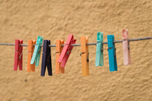 Abstract Shot Of Colorful Clothespins On A Washline Near Yellow Wall In Italy