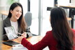 © NAMPIX - Two young attractive asian woman using tablet and discussing about business plan together while sitting at office.