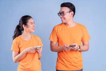 Wall Mural - Young Asian couple wearing orange t-shirt on blue background