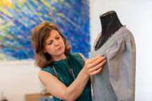 Female Fashion Designer Adjusting Fabric On Dummy At Studio