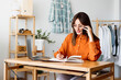 © Westend61 - Female fashion designer working at home sitting at desk taking notes