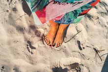 Mid adult woman with black nail polish on feet at beach on sunny day