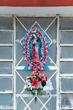 Virgin Mary Figurine With Flowers On Metal Grate