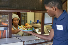 Young Waiter Taking Delivered Food From The Restaurant Kitchen, South Africa