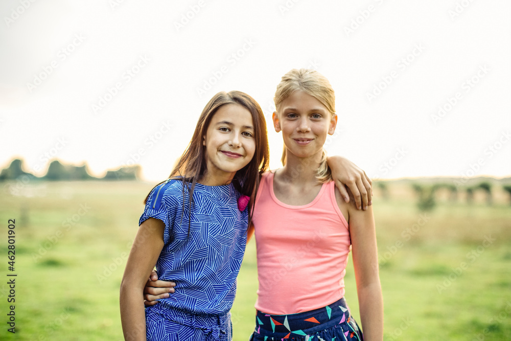 Portrait of two smiling girls embracing on a field Stock Photo | Adobe ...