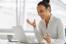 Smiling Female Entrepreneur Using Laptop On Desk In Home Office
