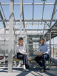 © Westend61 - Business people discussing over laptop while sitting on seat in greenhouse