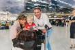 © Mareen Fischinger/Westend61 - Portrait of happy family with baggage cart at the airport