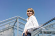 © Westend61 - Smiling female entrepreneur looking away while standing by railing against clear blue sky