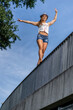 © Stefan Schurr/Westend61 - Smiling young woman balancing on a bridge railing