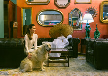 Smiling Woman With Dog Sitting On Couch In A Vintage Shop