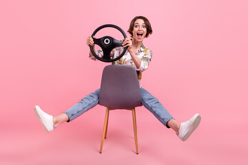 Poster - Full length body size photo woman riding on chair keeping steering wheel isolated pastel pink color background