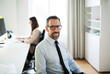 © Mike Schaefer/Westend61 - Portrait of confident businessman in office with employee in background