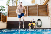 Little Girl Jumping With Uncle Into Swimming Pool